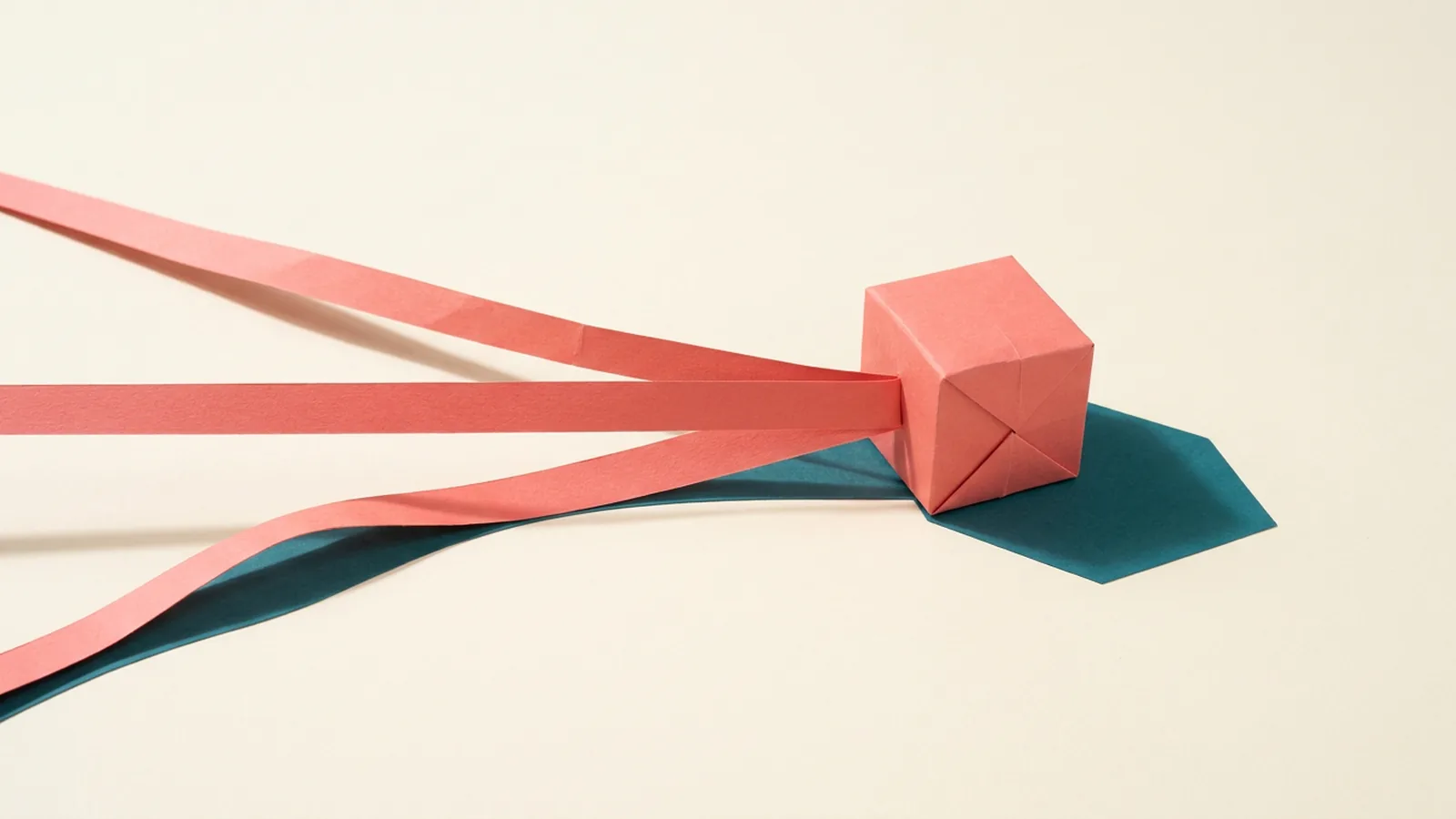Paper-craft illustration of three paper ribbons converging from the left edge on a single folded paper cube at the right: the middle ribbon runs straight and taut, the upper one straight at a downward angle, and the lower one sagging in a wave